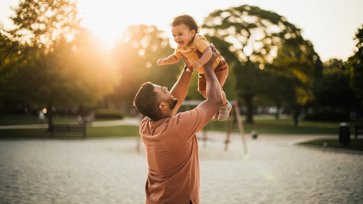 A single father playing with his young child outdoors.