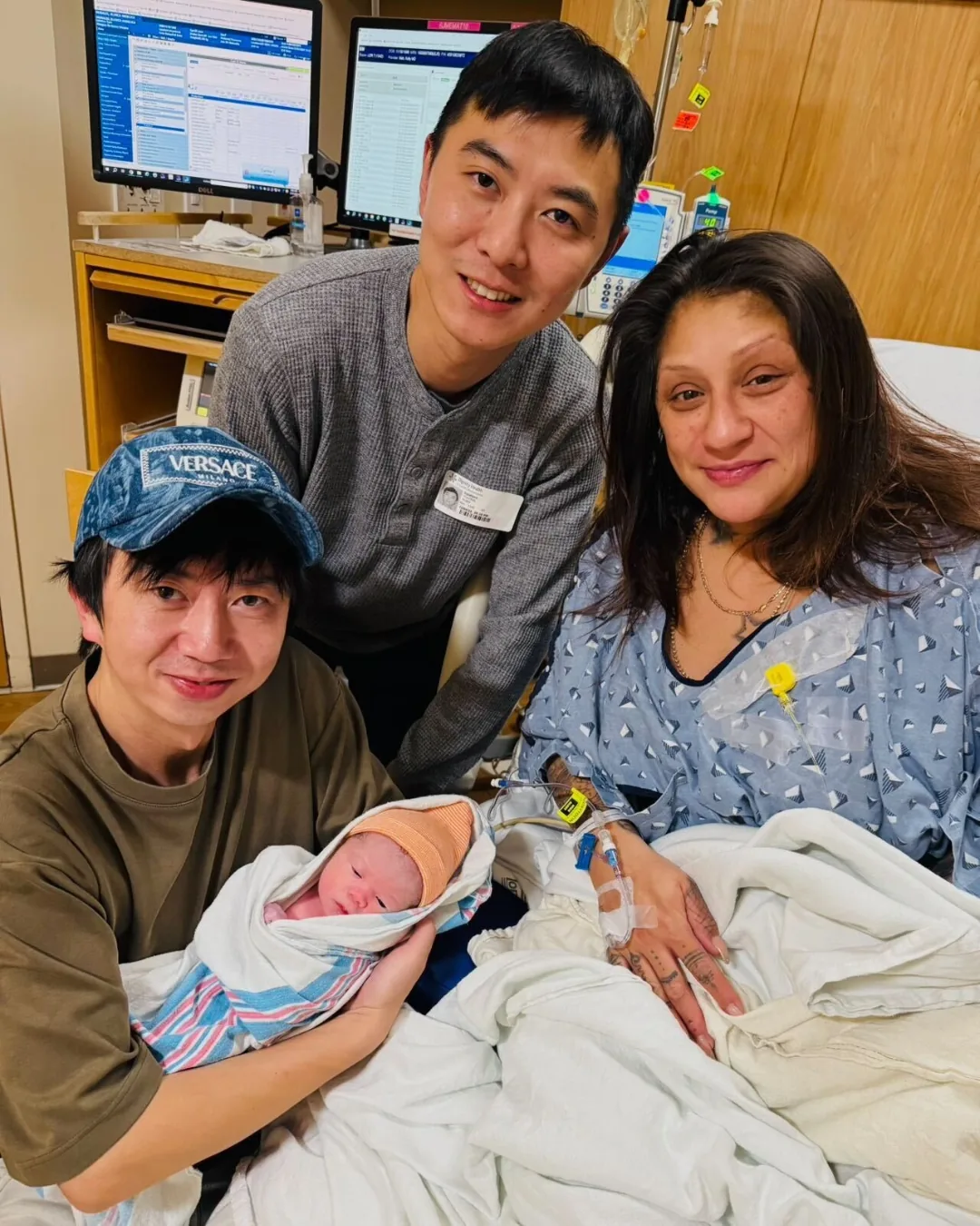 Two intended fathers and their surrogate together with their newborn at the hospital after delivery