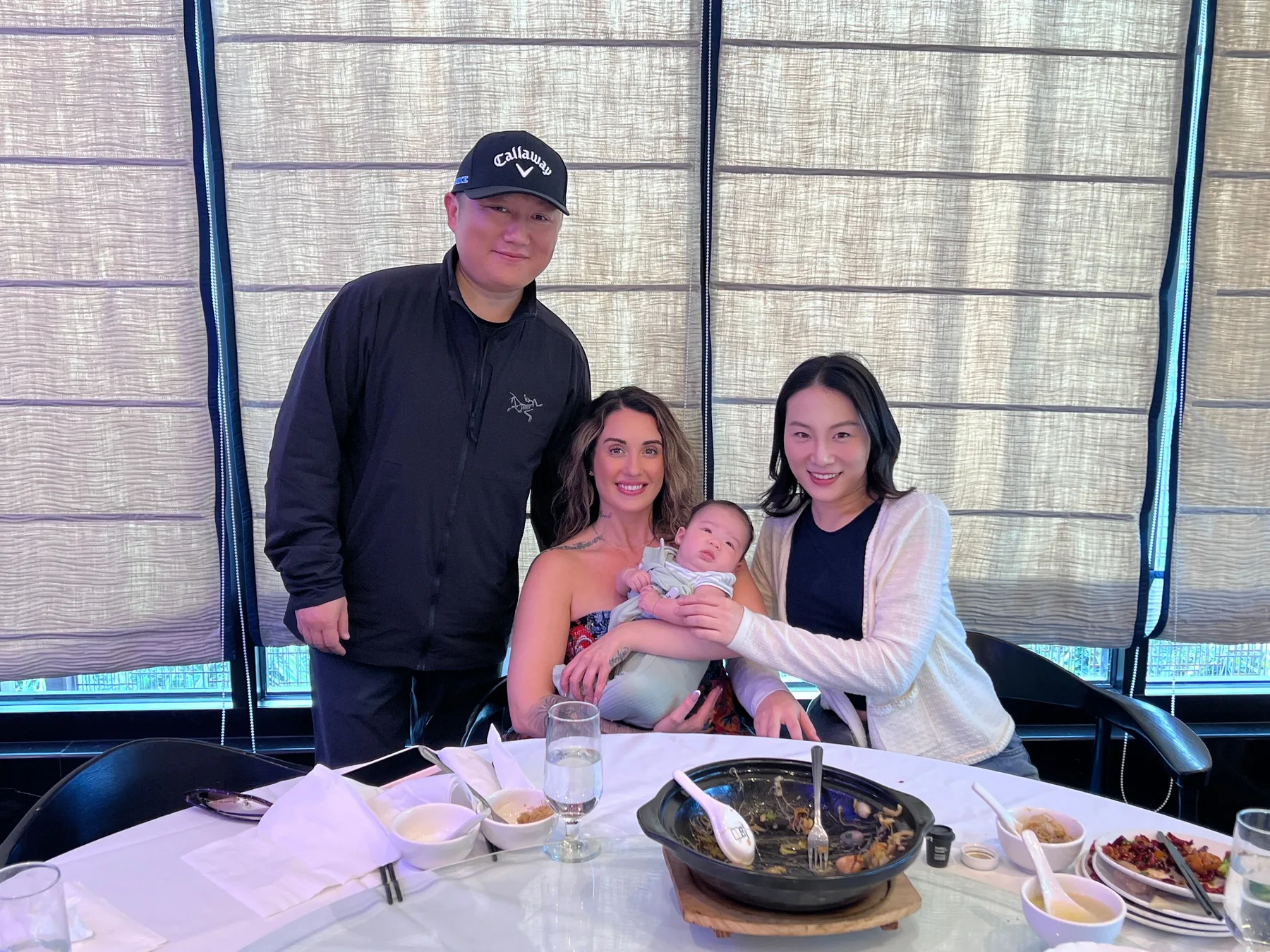 Intended parents, their surrogate, and their baby sharing a meal together.